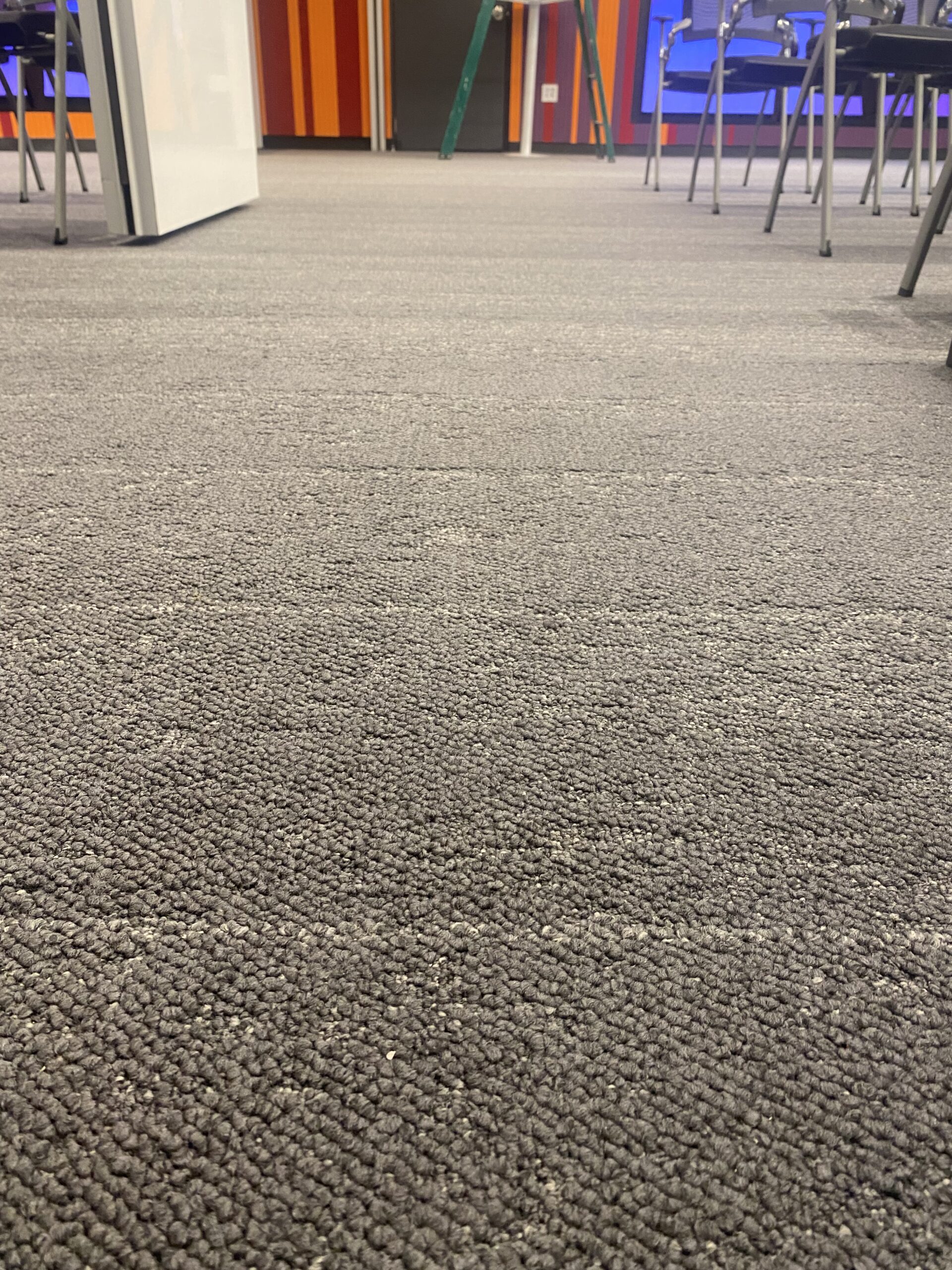 Vista cercana de una alfombra gris en un ambiente de oficina.