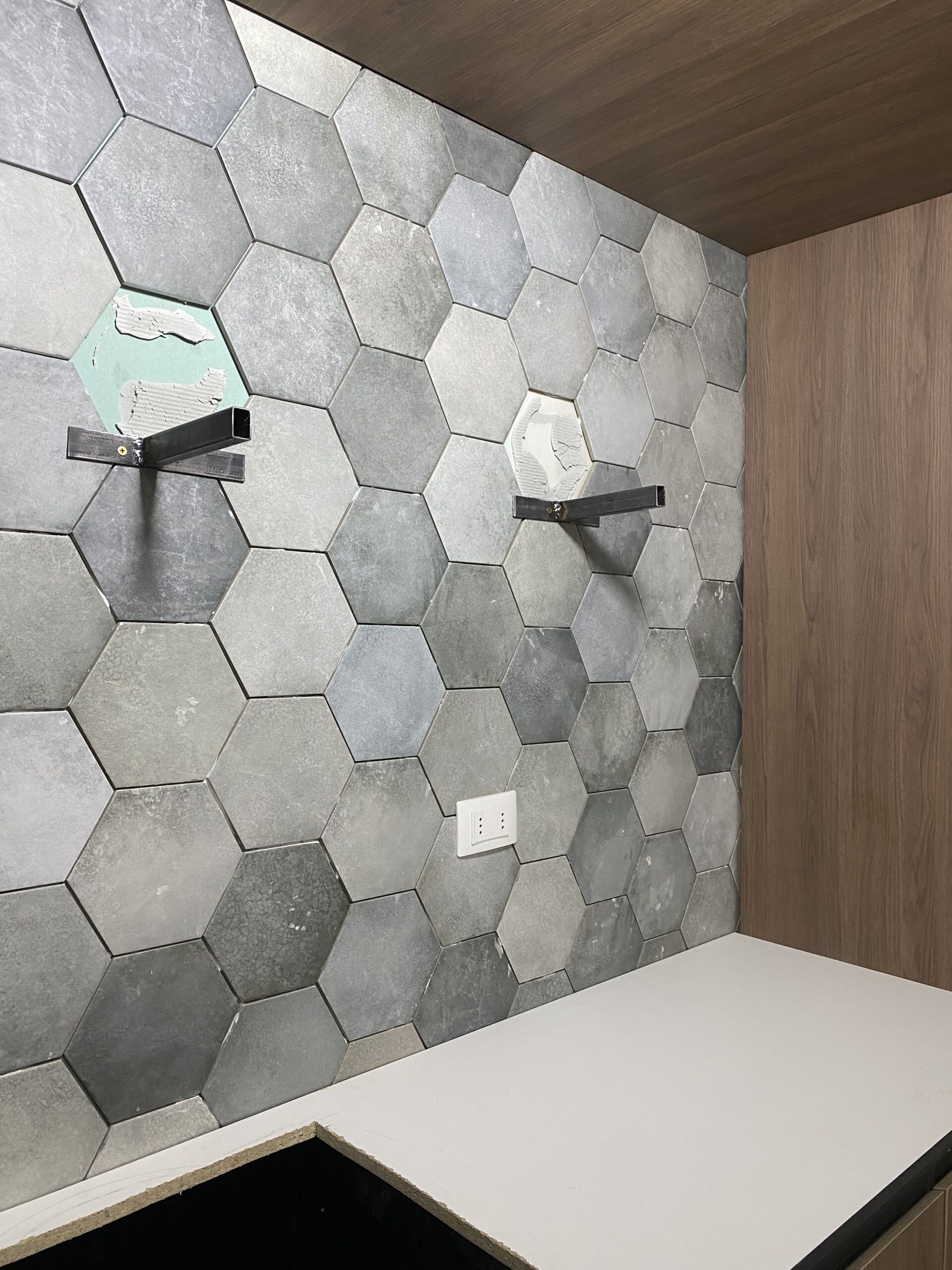 Revestimiento de piezas hexagonales en tonos grises sobre una cubierta clara.