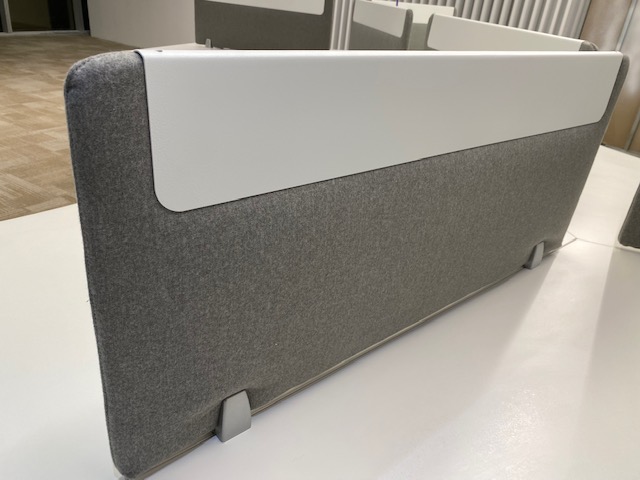 Separador gris de escritorio con una pieza blanca sobre una mesa de trabajo.