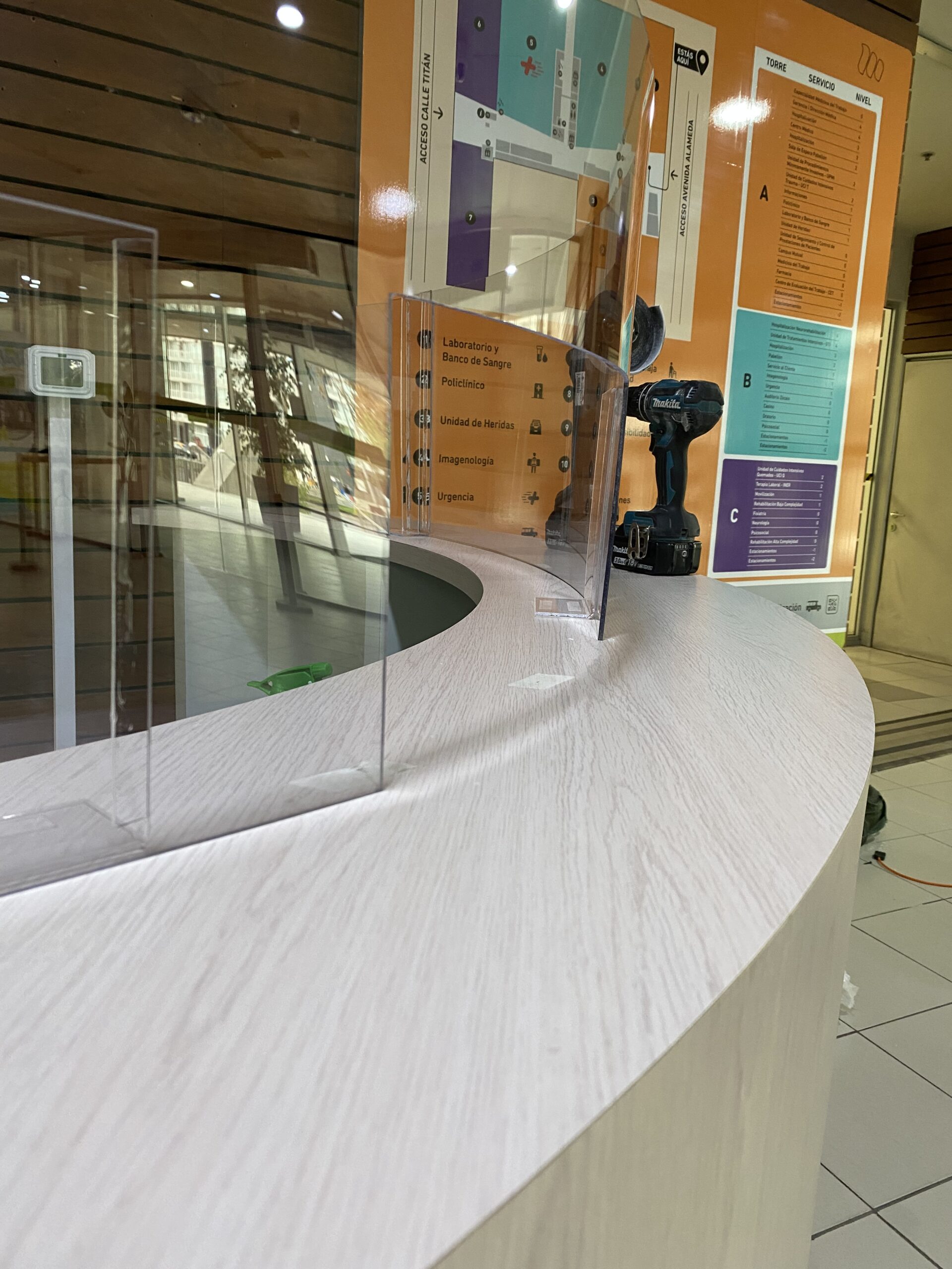 Detalle de un mostrador curvo claro con pantalla transparente en una recepción.